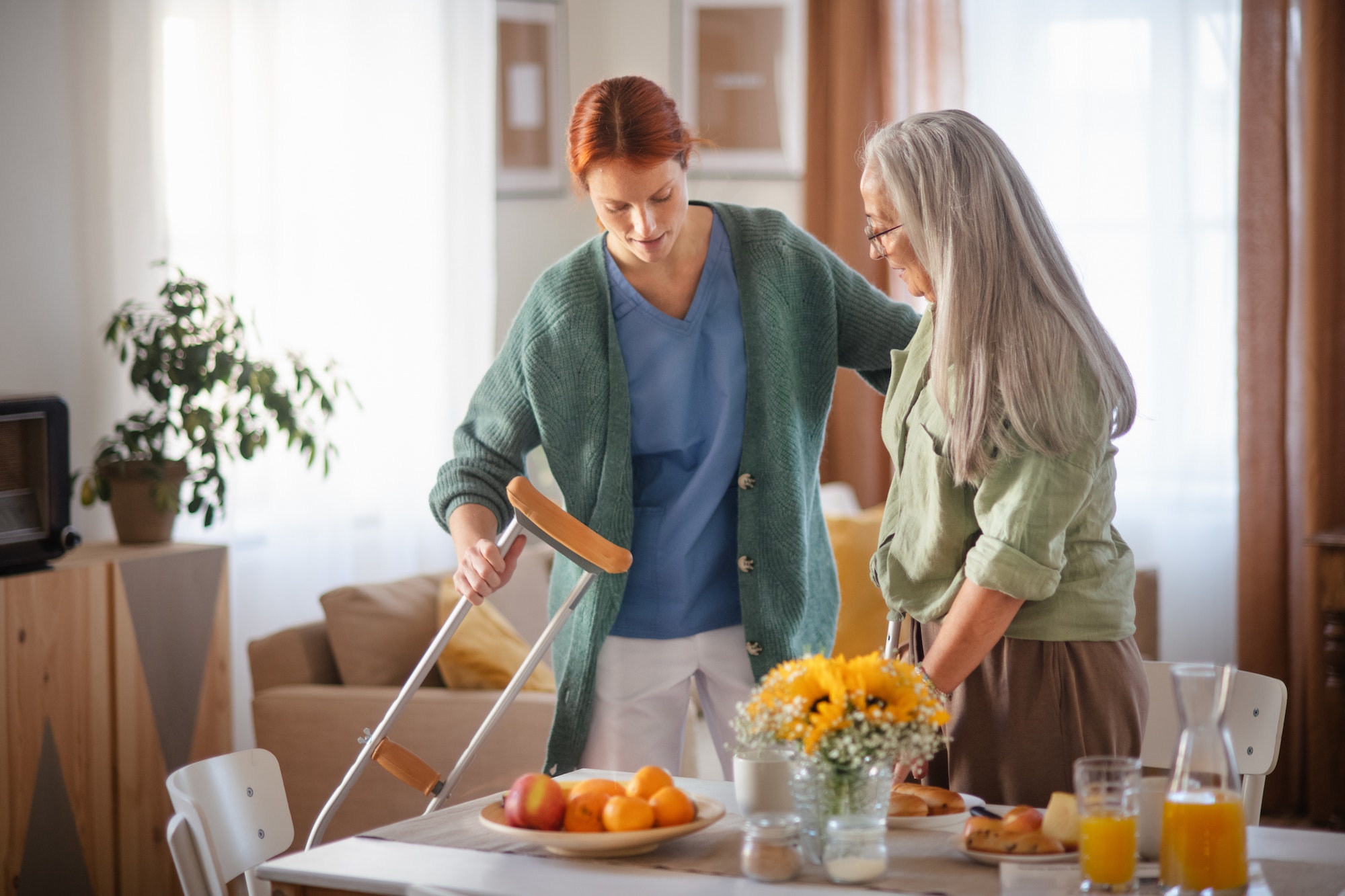 Nurse helping senior woman with walking after leg injury.