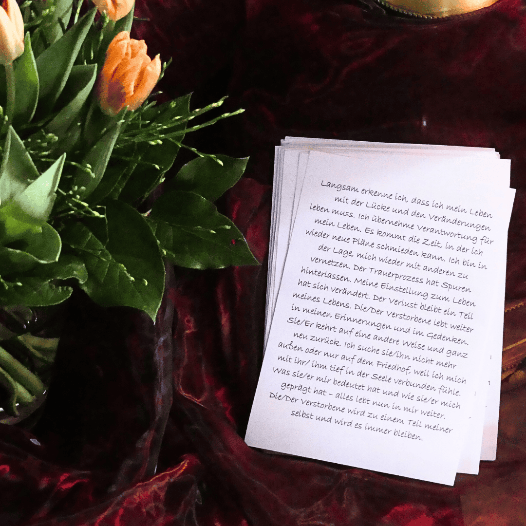Ein Blumenstrauß mit Tulpen neben einem Stapel Papier auf einem roten Samttuch.
