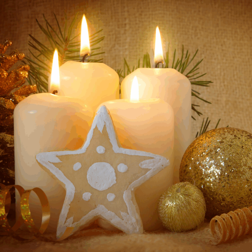 Vier brennende Kerzen, Stern-Dekoration und goldene Kugeln im warmen, festlichen Arrangement.