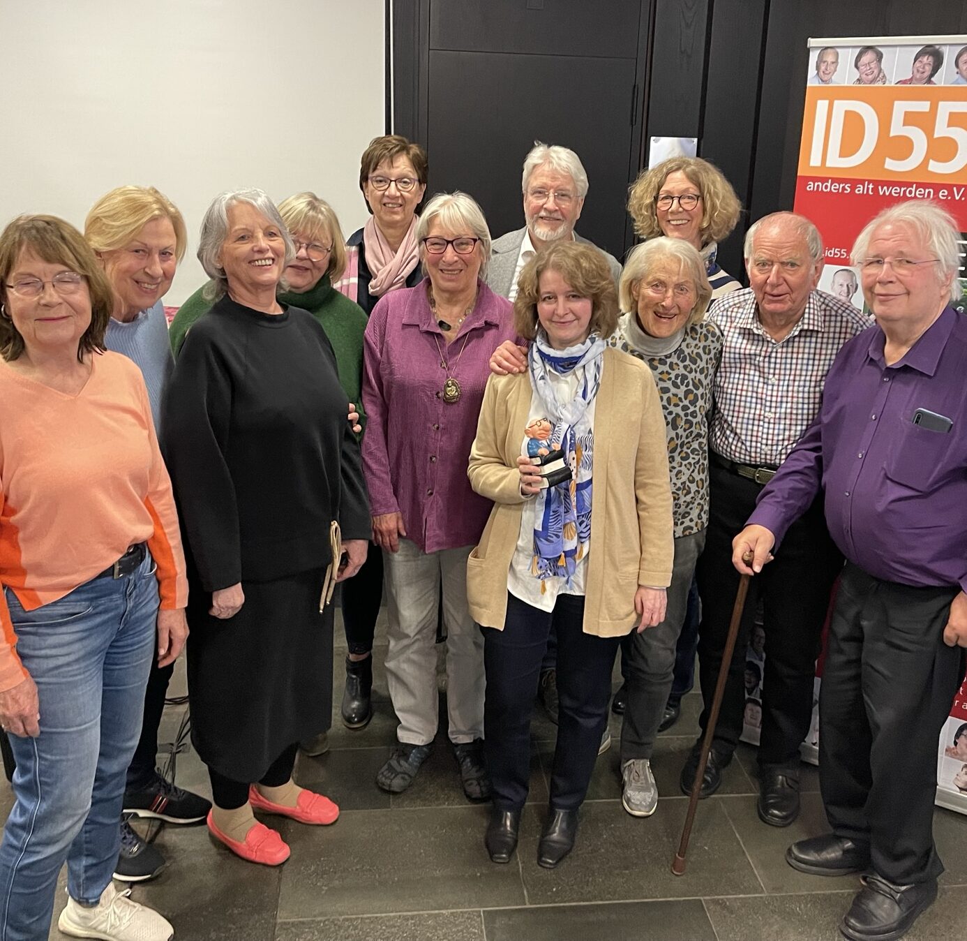 Gruppe von älteren Menschen bei einem Treffen von ID55, lächeln in die Kamera.